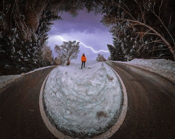 Rear view of man on snow covered road against sky