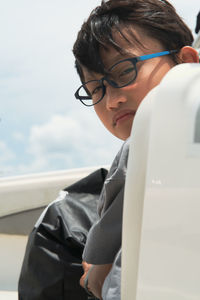 Asian boy wearing glasses looking at the camera on a boat.