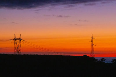 Silhouette electricity pylon against romantic sky at sunset