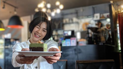 Smiling young woman holding ice cream at store