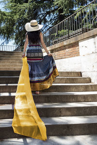 Rear view of woman holding umbrella on staircase