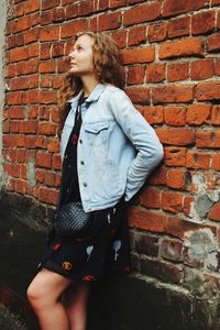 Young woman standing against brick wall