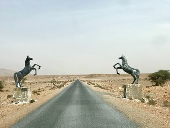 Statue on road against sky