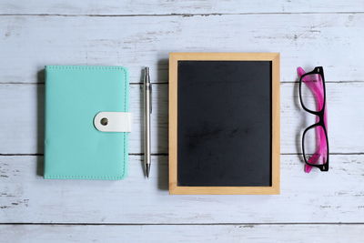 Directly above shot of writing slate with diary and pen on table