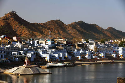 Residential district amidst mountains and lake against clear sky