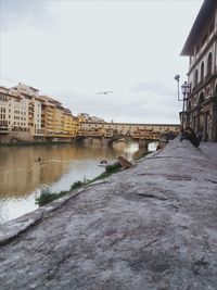 Buildings by river against sky in city