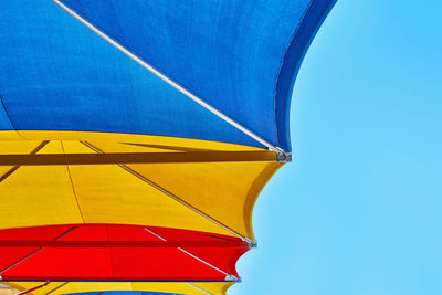 Low angle view of yellow umbrella against clear blue sky