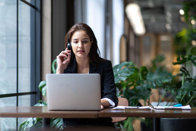 Young woman using phone while sitting on table