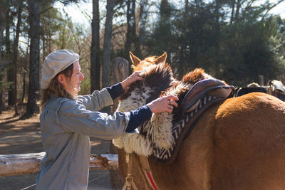 Side view of woman standing by horse in forest