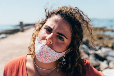 Portrait of young woman at beach against sky