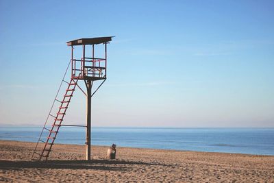 Lifeguard hut on beach against clear blue sky