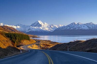 Road by snowcapped mountains against sky