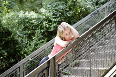 Thoughtful woman leaning on railing