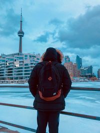 Rear view of man standing by buildings against sky