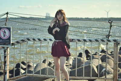 Woman standing by railing against sky