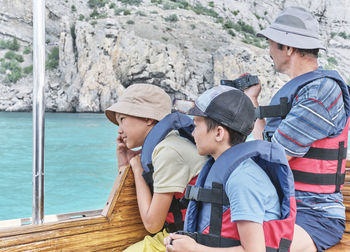 Grandfather and his two grandsons, in life jackets trip on pleasure boat on the sea. 