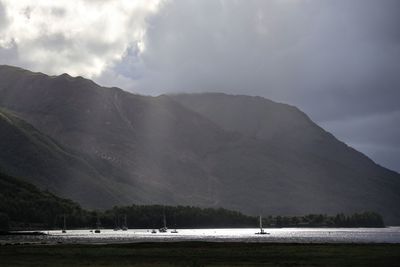 Scenic view of lake by mountains against sky