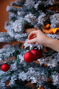 Cropped hand of woman holding christmas decoration on christmas tree