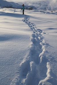 Woman hiking with footprints on snow covered field
