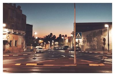 Illuminated city against sky at sunset