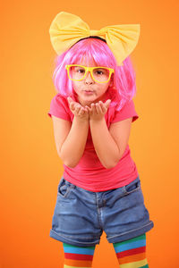 Portrait of beautiful young woman standing against yellow background