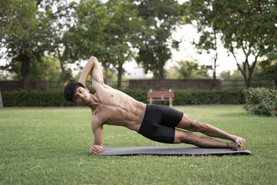 Full length of shirtless man lying on grass