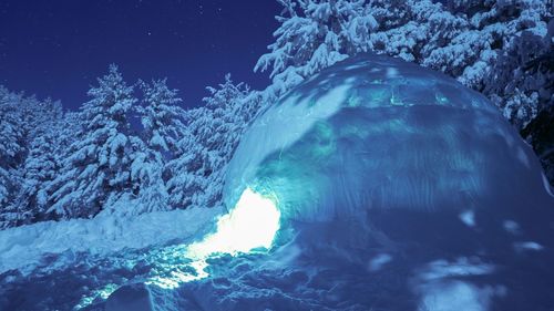 Low angle view of snow covered landscape against blue sky