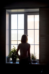 Rear view of woman standing by window