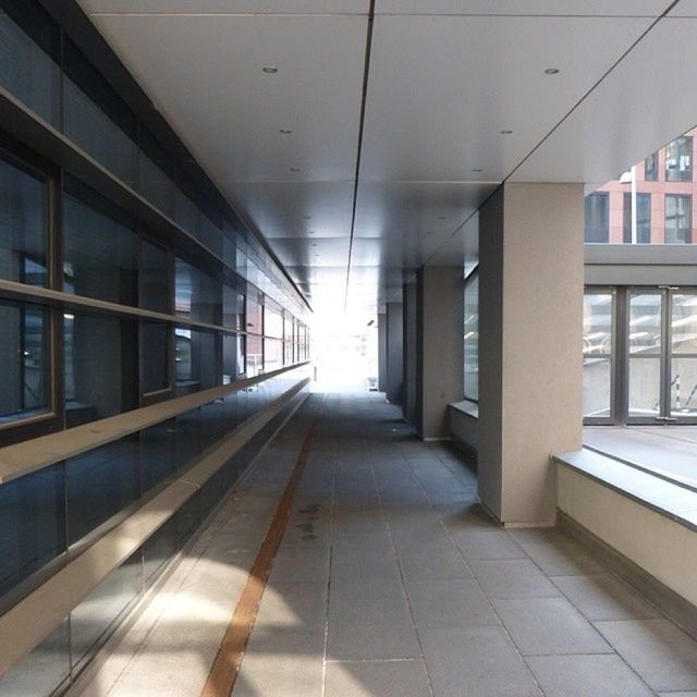 indoors, architecture, built structure, corridor, ceiling, flooring, empty, the way forward, tiled floor, absence, interior, modern, diminishing perspective, tile, building, reflection, no people, window, glass - material, door