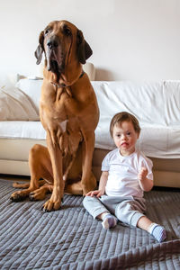 Disabled boy with dog sitting on carpet at home