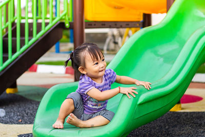 Happy boy sitting on slide at playground