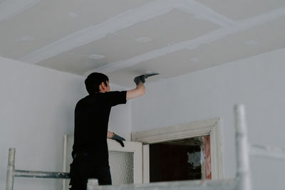 One young worker is cleaning the ceiling with a spatula.