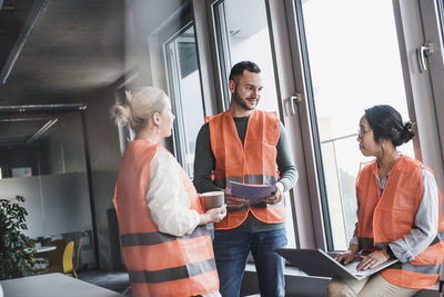 Multiracial colleagues wearing reflective clothing planning strategy together at workplace