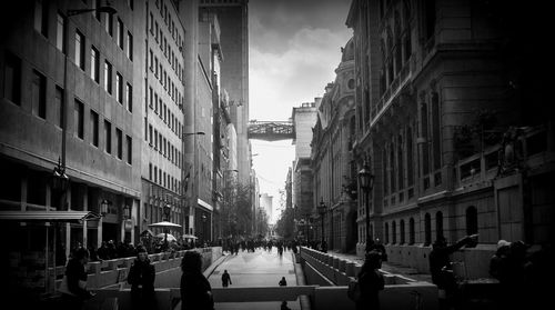 People walking on street amidst buildings in city