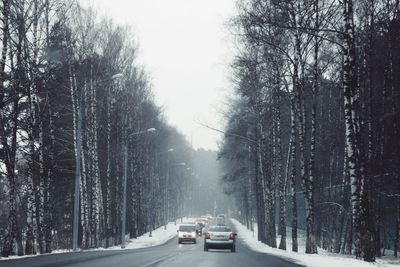 Cars on road in winter against sky