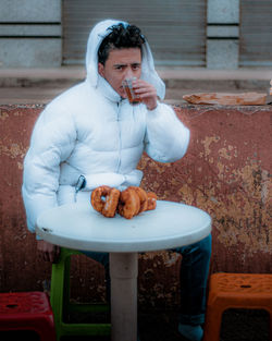 Portrait of young man having drink outdoors