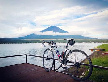 Bicycle by lake against sky