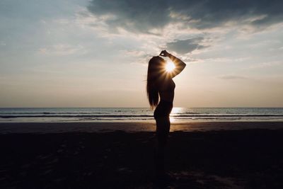 Man standing on beach against sky during sunset