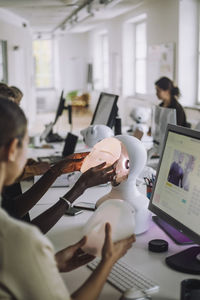 Multiracial students discussing over social robot at desk in innovation lab