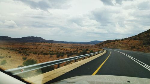 Scenic view of road by mountains against sky
