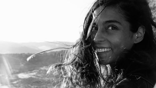 Close-up portrait of smiling young woman against clear sky