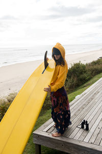 Female surfer prepares her surfboard for adventure