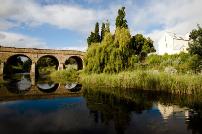 Arch bridge over river against sky