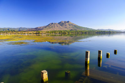 Scenic view of lake by mountains against clear blue sky