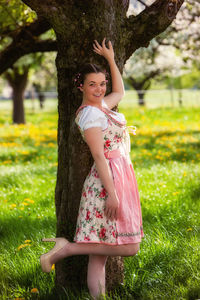 Portrait of smiling girl standing on grass against trees