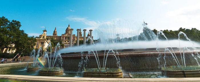 Fountain in city against sky