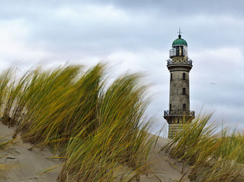 Lighthouse on beach against sky