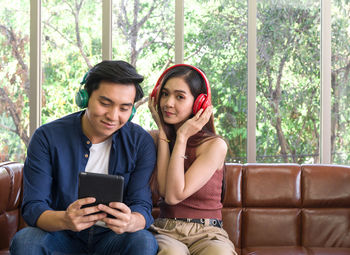 Young couple looking at camera while sitting on sofa