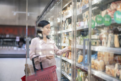 Young woman shopping during inflation in supermarket