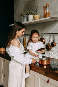 Month and daughter preparing food at kitchen counter